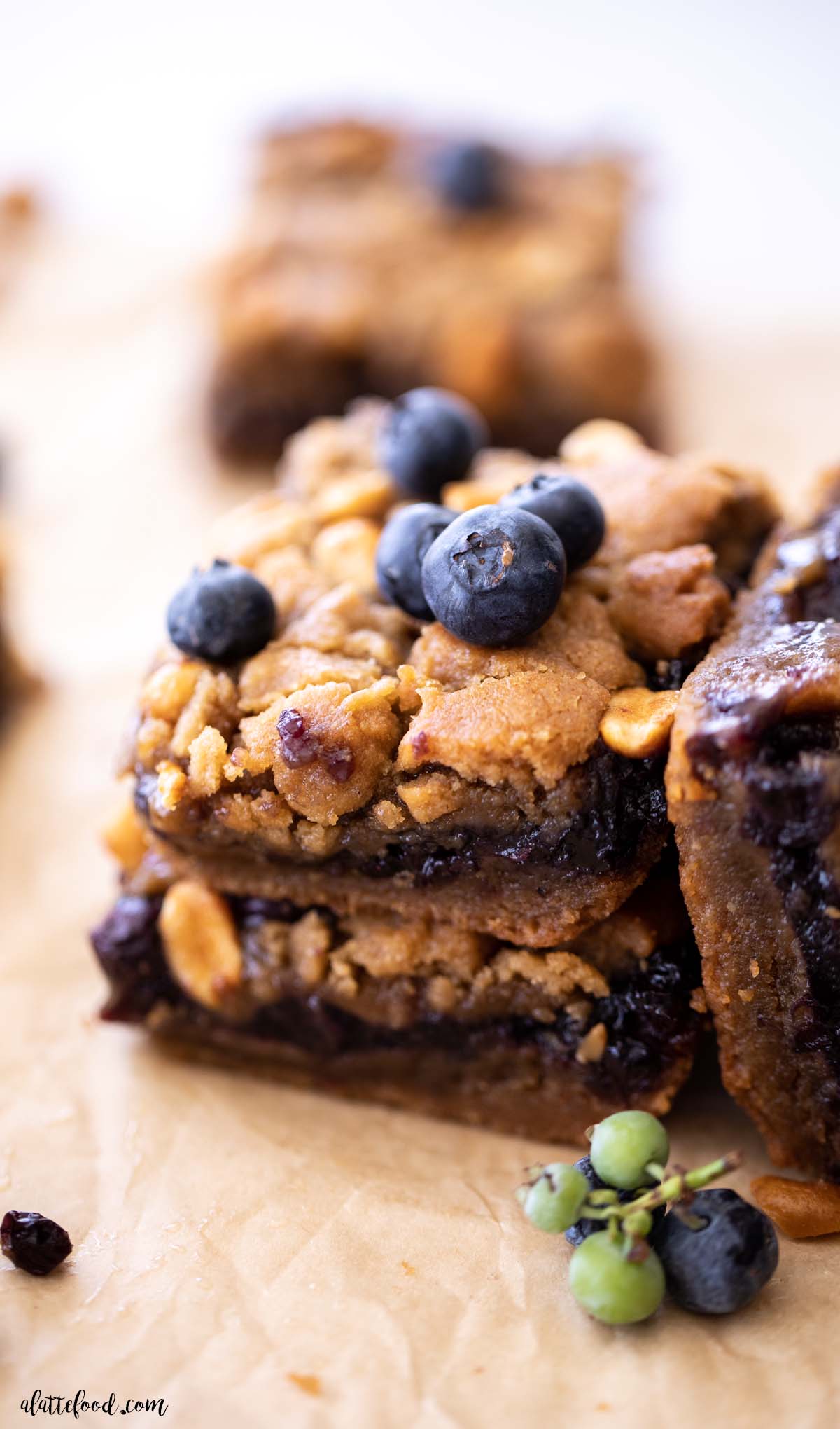 Stack of PB&J cookie bars with honey roasted peanuts and fresh blueberries on top