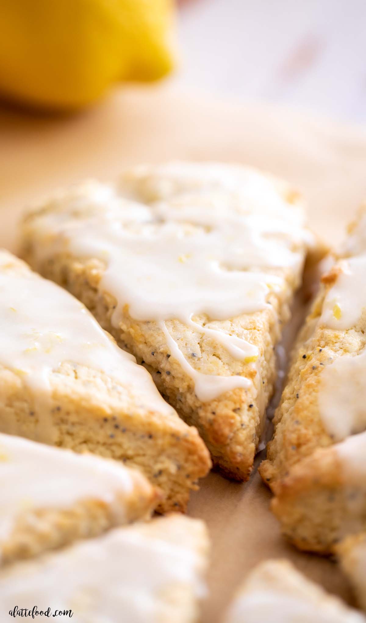 lemon poppyseed scone with lemon glaze on brown parchment paper