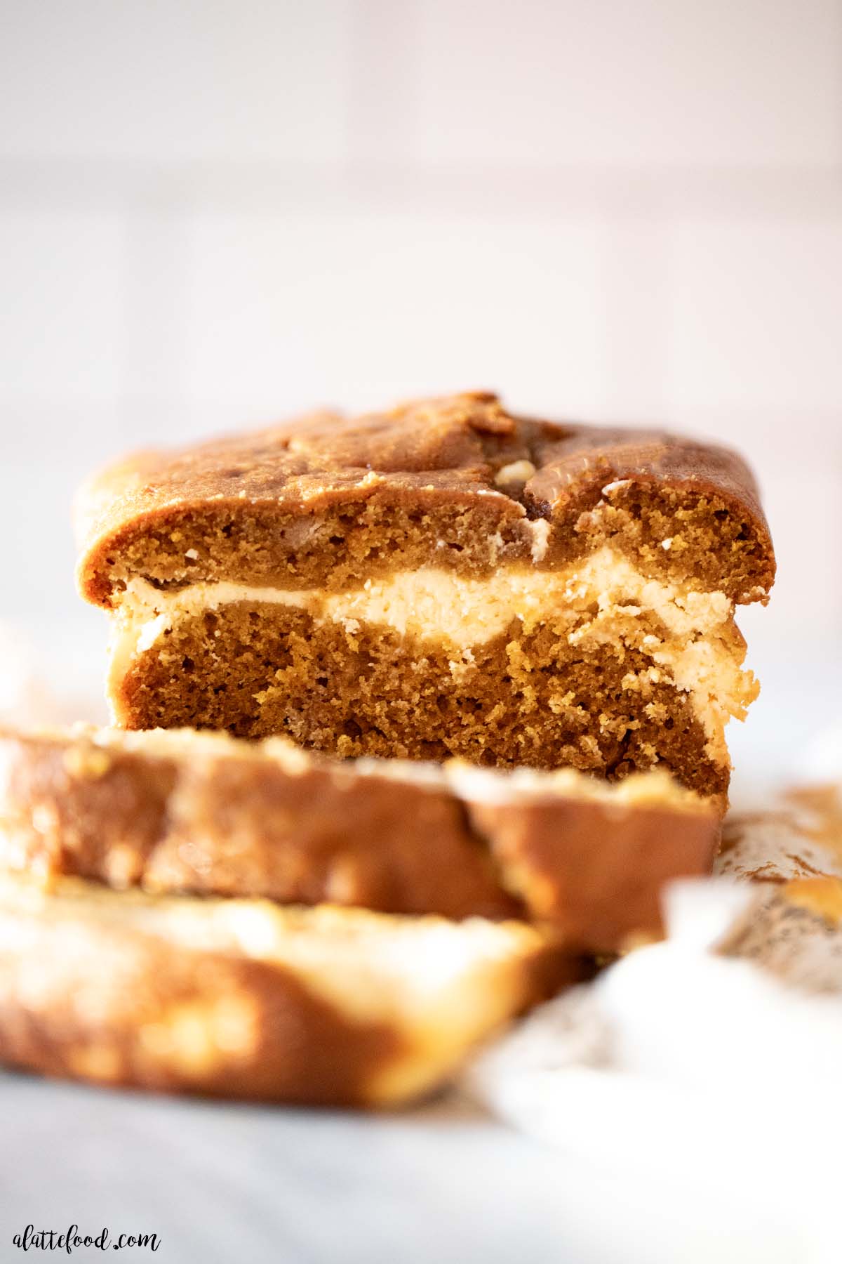 baked cream cheese pumpkin bread sliced with a ribbon of cheesecake filling in the center. 